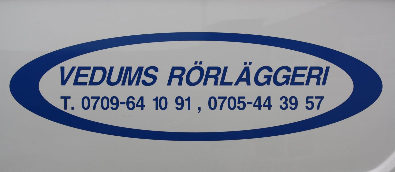 Logotypen Vedums Rörläggeri med telefonnummer på en av firmans servicebilar